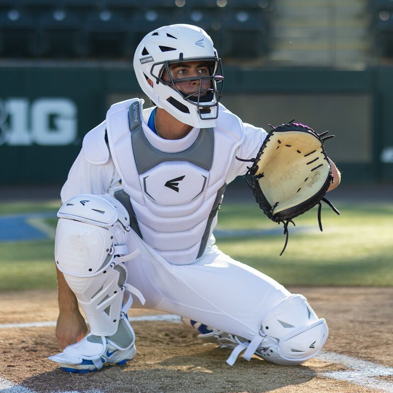 Catcher in white Easton Mavrix chest protector, helmet, and leg guards in receiving position at home plate
